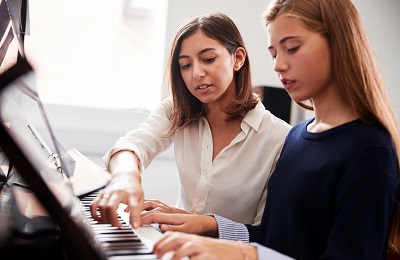 piano teacher and student
            sitting at a piano